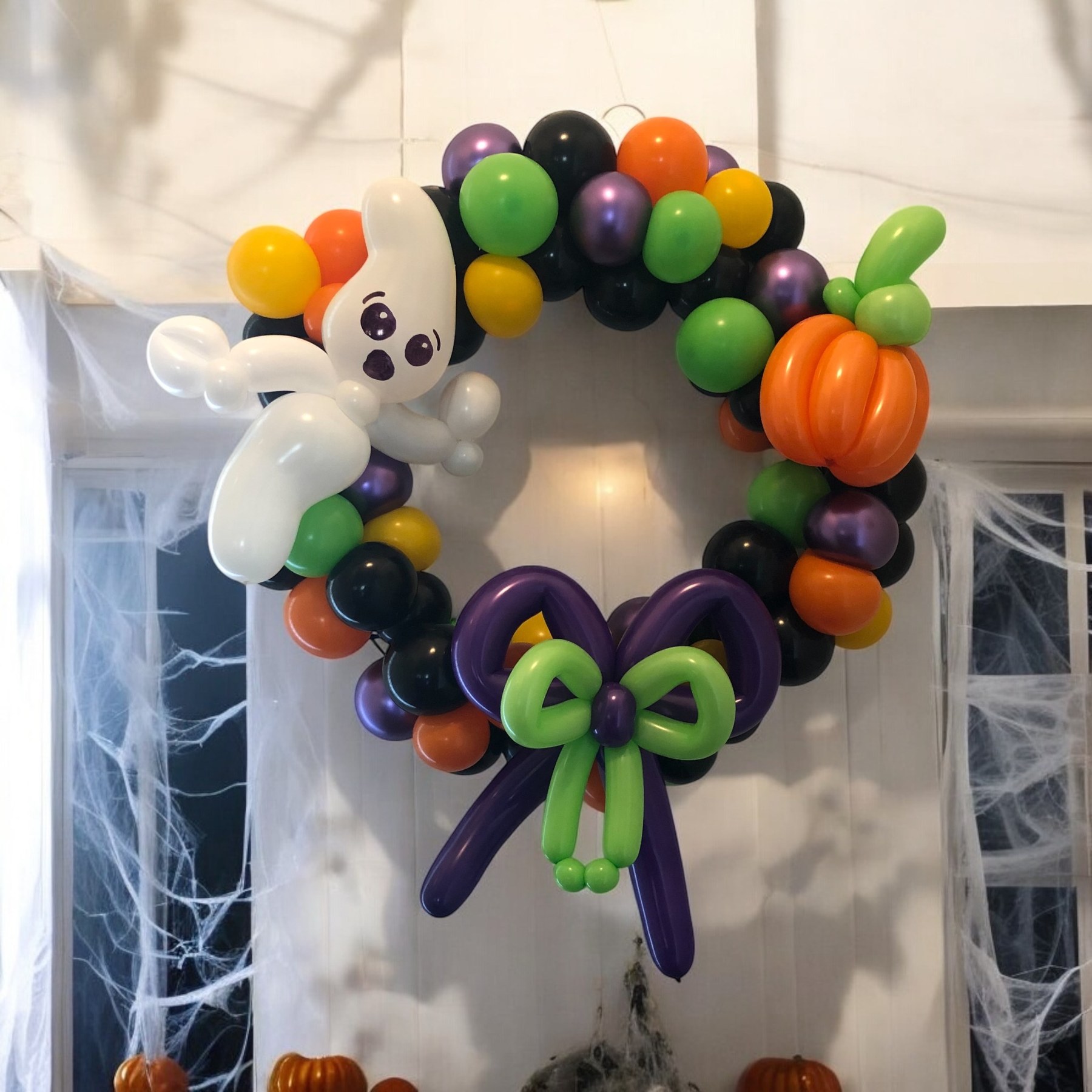 Halloween balloon wreath by Whimsy Entertainment with a balloon ghost, pumpkin, bow and colorful balloon garland.