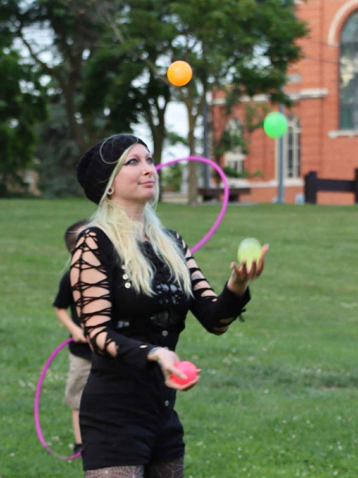 Balloon twisting party entertainment in Virginia Beach as Saria “Blu” Braska creates swords, animals and wearable balloon art for children and adults at a lively backyard celebration.